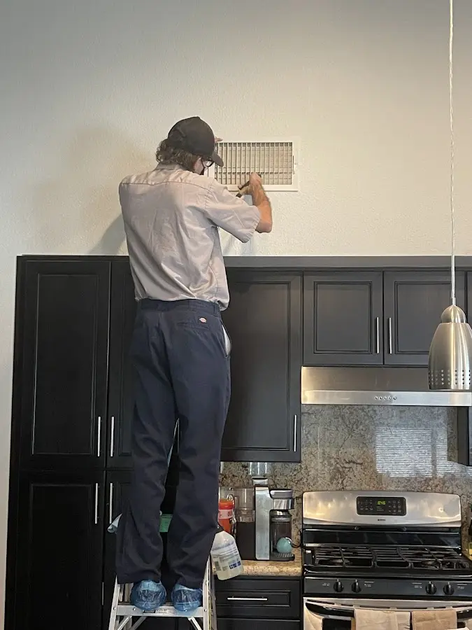 Technician inspecting an air vent during HVAC service in Twentynine Palms